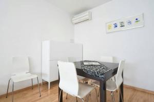 巴塞罗那Apartamento Noemi的一间用餐室,配有黑桌和白色椅子
