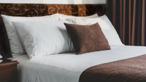 利马法拉奥纳大酒店的一张带白色枕头和棕色枕头的床