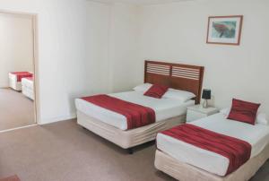 布里斯班Acacia Ridge Hotel & Motel Brisbane的一间卧室配有两张床和镜子