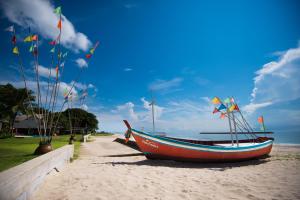 哈德超珊兰哈德巢萨姆蓝渔夫度假村 的海滩上的船,上面有旗帜