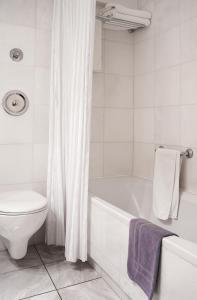 雅典伊利索斯酒店的白色的浴室设有浴缸和卫生间。