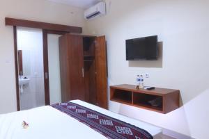 沙努尔Sekar Waru Homestay的卧室配有一张床,墙上配有电视。