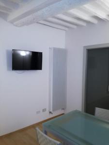 锡耶纳La casa in Camollia的客厅配有桌子和墙上的电视