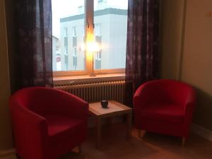 斯特伦松德Grand Hotell的窗前的两张红色椅子和一张桌子