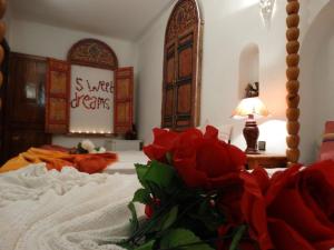 马拉喀什Riad Sérénis的一间卧室,床上有红色玫瑰