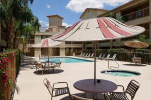 卡萨格兰德Siegel Select Casa Grande的一个带遮阳伞和椅子的庭院和一个游泳池