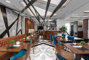 贝尔格莱德天空酒店的餐厅设有木桌和蓝色椅子