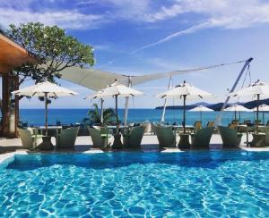 卡马拉海滩Cape Sienna Phuket Gourmet Hotel & Villas - SHA Extra Plus的一个带椅子和遮阳伞的游泳池以及大海