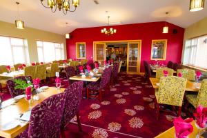 拉恩柯伦苑酒店的一间设有桌椅和红色墙壁的餐厅