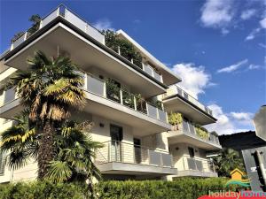 加尔达湖滨Apartament Gardasee的一座白色的建筑,前面有棕榈树