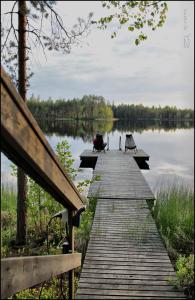 RastinniemiKultajärvi Holiday Home的木板人行道通往带长凳的湖泊