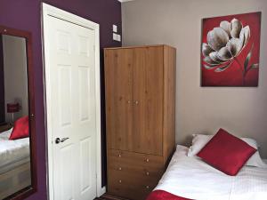南安普敦Glenmore Guesthouse的一间卧室配有一张床和一个带红色枕头的橱柜