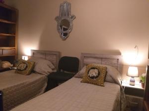 埃尔哥茨拉Lotus Guest House Malta的一间卧室配有两张床、一把椅子和一个吊灯。