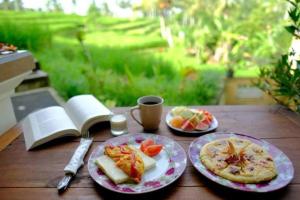 贾蒂卢维Adhi Jaya Suite的餐桌,带两盘食物和一杯咖啡的桌子