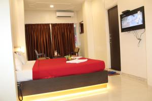 浦那Choice Classic Hotel的酒店客房配有红色的床和平面电视。