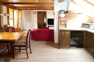 因特拉肯罗斯利假日公寓的厨房以及带桌子和红色沙发的用餐室。