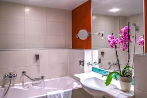 哈卡尼Dráva Hotel Thermal Resort的浴室配有白色浴缸、水槽和花卉