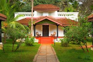 库姆巴科纳姆Mantra Koodam Kumbakonam-CGH Earth的一间白色的小房子,设有红色的门和椅子