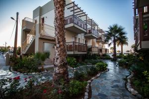 罗希姆诺伊利安海滩公寓式酒店的一座带走道和棕榈树的度假建筑