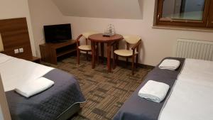 卢托维斯卡Centrum Promocji Leśnictwa w Mucznem的酒店客房设有两张床、一张小桌子和一张桌子。