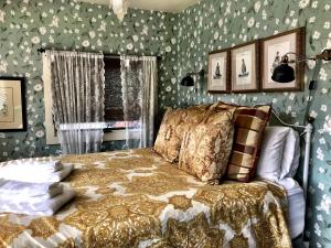 史凯威Historic Skagway Inn的一间卧室配有一张带花卉壁纸的床