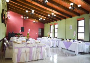 瓦曼特拉Hotel Las Candelas de Huamantla的配有桌椅和白色桌布的房间