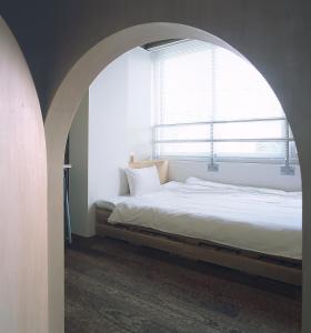 Akune沙丁鱼大厦旅舍的卧室设有拱门、一张床和一个窗户