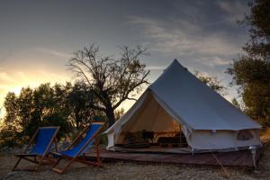 诺托Shauri Glamping的白色帐篷,配有2把蓝色椅子和日落