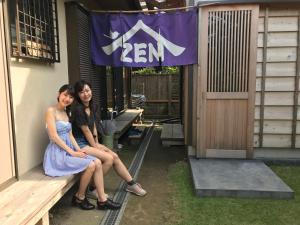 镰仓市镰仓泽杰旅馆的两个年轻的女人坐在大楼前的长凳上