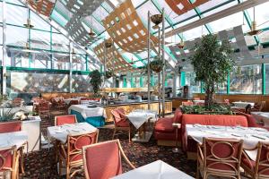 阿萨哥皇家花园酒店的一间设有桌椅的餐厅,位于带窗户的房间内
