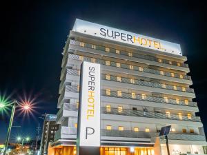 HigashineSuper Hotel Yamagata Sakurambo-Higashine Station Front的前面有超级酒店标志的建筑