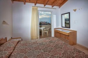 罗希姆诺伊利安海滩公寓式酒店的一间卧室配有一张床、一张书桌和一个窗户。