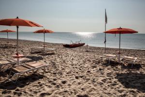 马里纳皮斯蒂奇马塞里亚马基亚及雷莱斯萨恩皮奥乡村民宿的海滩上设有遮阳伞、椅子和船只