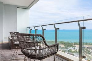 三亚三亚海棠湾艾诺拜海景酒店式公寓的藤椅,坐在俯瞰大海的阳台