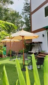 查汶Top Hostel Samui的一个带桌椅和遮阳伞的庭院