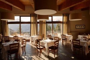 萨奥兹-杜尔克斯Chaberton Lodge & Spa的餐厅设有白色的桌椅和大窗户。