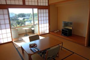 志摩市Kashikojima Hotel Bay Garden的客厅配有桌子和电视