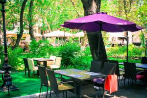 敖德萨Hotel MAMAN的一张紫色的伞,坐在桌子和椅子旁边