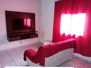 卡瓦坎特Pousada da Ana的客厅配有电视和红色窗帘
