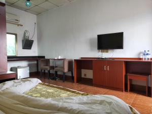 帝力CHONG TI HOTEL的客房设有一张床和一张书桌上的电视