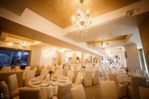 比斯特里察奥扎纳酒店的宴会厅配有白色的桌椅和吊灯