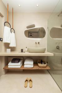 基斯诺斯Chora Kythnos Suites adults only的浴室设有水槽和一个带毛巾及鞋子的架子