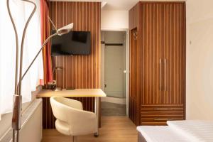 克洛斯特新堡安克酒店的一间卧室配有书桌、椅子和电视。
