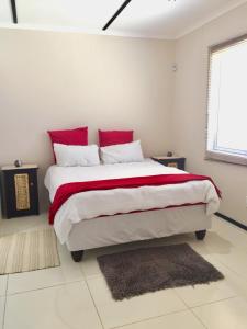 斯瓦科普蒙德Man Cave Suite的白色卧室配有一张带红色枕头的大床