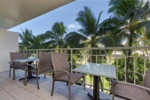 檀香山CASTLE Waikīkī Shores的阳台配有桌椅和棕榈树