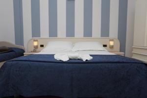 里米尼日光酒店的一间卧室配有一张床,上面有两条毛巾