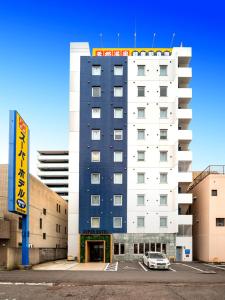 高松Super Hotel Takamatsu Kin en kan的前面有停车位的建筑