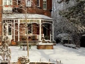 根特爱玛别墅住宿加早餐旅馆的雪覆盖的房子,前面有一个喷泉