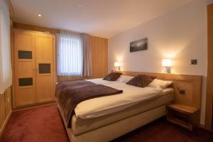 采尔马特阿尔卑斯洛奇酒店的一间卧室配有一张大床和两盏灯。