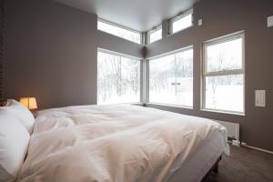 二世古Mountain Butterfly的卧室设有一张大白色的床铺,设有窗户